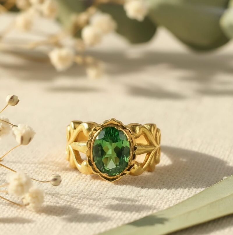 Gold statement ring with oval green stone and leaf shoulders