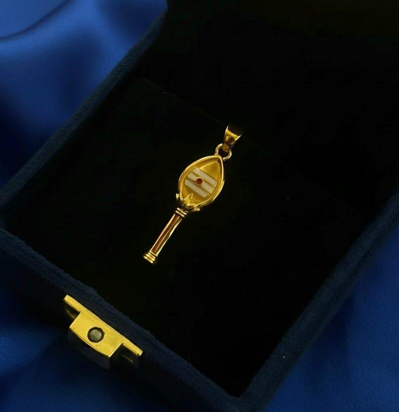 Gold key-style pendant with engraved face