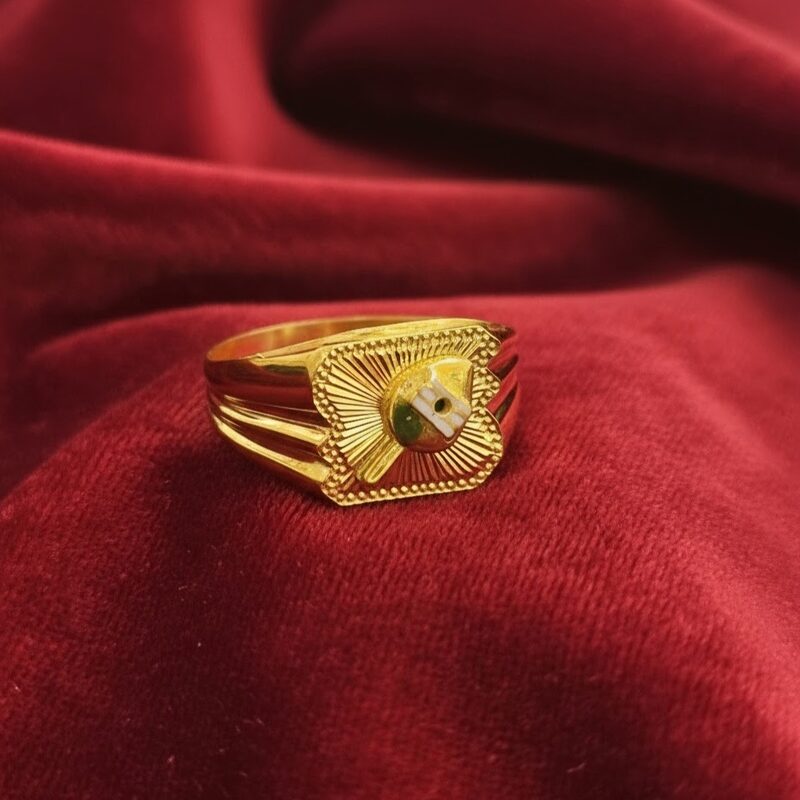Gold signet ring with sunburst-engraved face and green accent